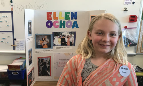 student posing in front of her presentation board 